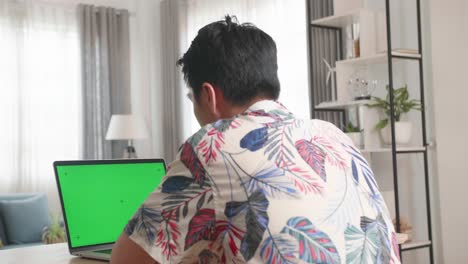 Asian Man Using Laptop Computer With Green Screen At Home