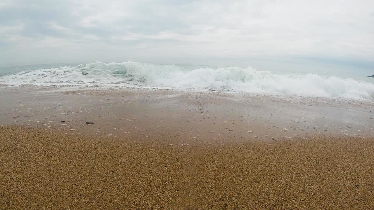 파도가 느린 움직임으로 모래 해변을 향해 부 ⁇ 히고