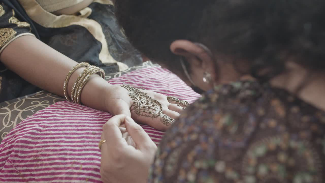 Artista che applica un tatuaggio Mehndi sulla mano della sposa