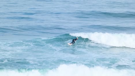 Close-view-of-a-surfer-performing-a-powerful-snap,-sending-a-spray-of-water-on-a-perfect-wave