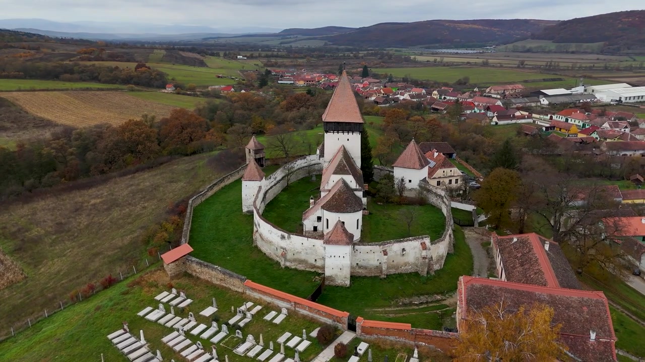Vychutnejte si plnou krásu opevněného kostela v Hosmanu v Transylvánii v Rumunsku s těmito dynamickými záběry z dronu. Obletí kostel, opevněné zdi a úchvatnou podzimní krajinu kolem něj.