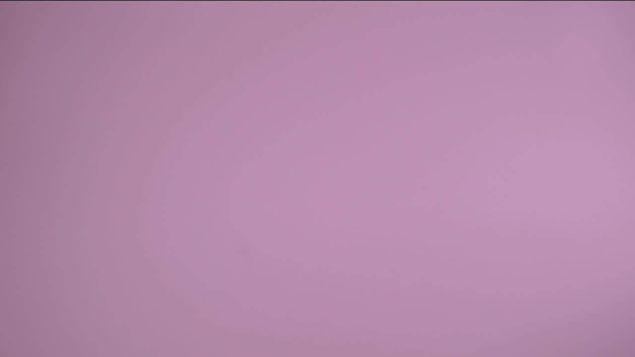 pequeñas bolas de vidrio verde esmeralda saltando en el aire y cayendo en cámara lenta con fondo rosa