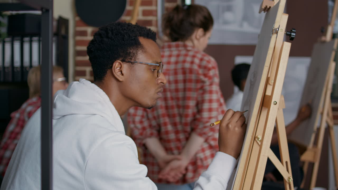 Portrait of young student using pencil on canvas to draw vase
