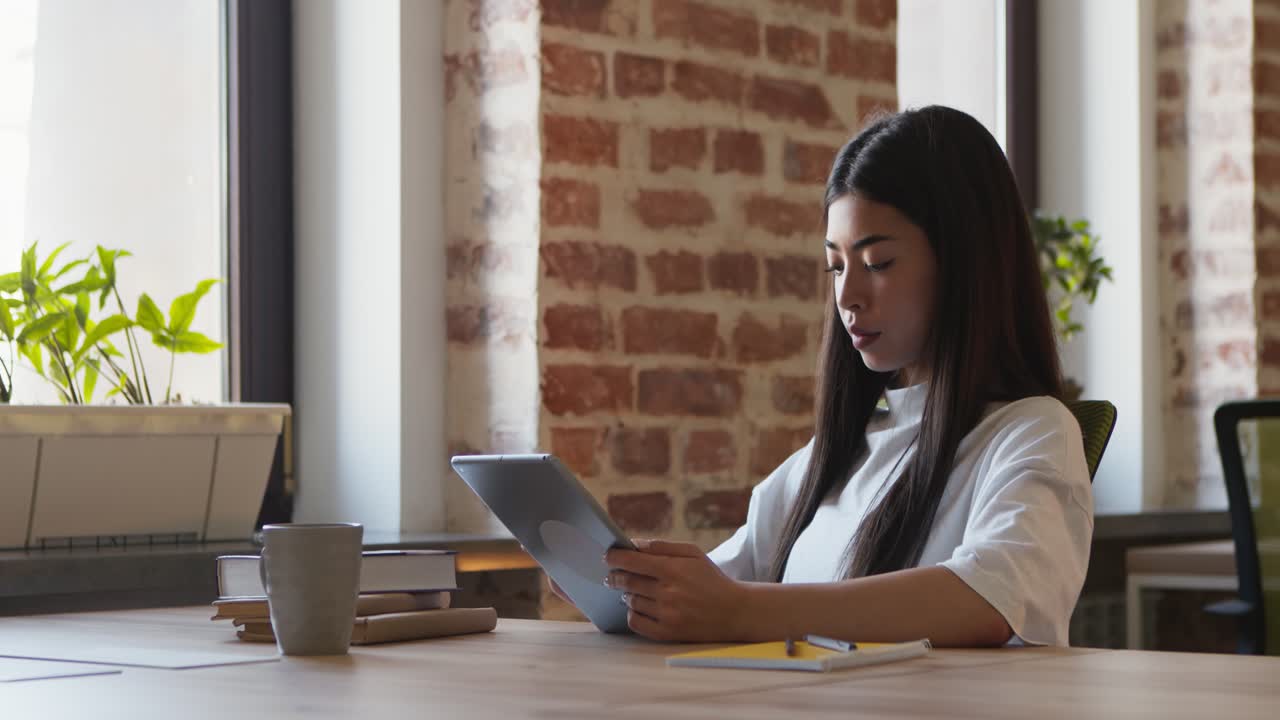 mujer joven trabajando en una tableta digital en una oficina