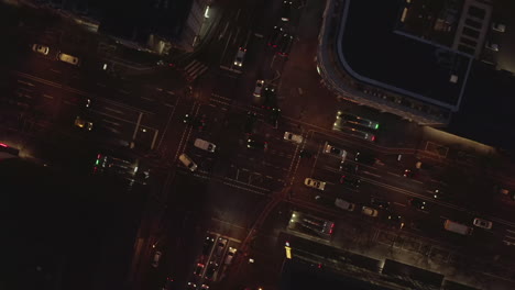 AERIAL:-Beautiful-Overhead-Shot-of-busy-intersection-at-night-with-Car-traffic-and-city-lights
