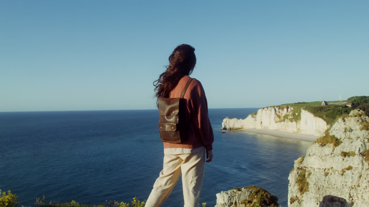 mujer caminando por los acantilados con vistas al océano