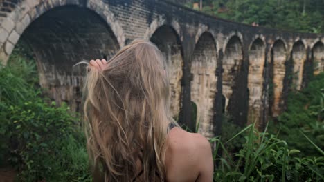 a female traveler visits the famous nine arch bridge in ella, a colonial-era viaduct nestled in the lush hill country of sri lanka.
