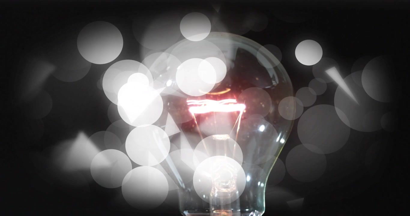 Video vertical: Bombilla clara que se ilumina con filamento brillante después de encenderse, bokeh de estudio con triángulos en movimiento