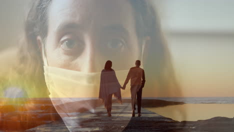 digital composite video of woman wearing face mask against couple walking on a beach in background