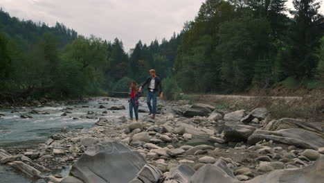 Frau-Und-Mann-Gehen-Auf-Felsen-Am-Flussufer.-Touristen-Wandern-In-Den-Bergen