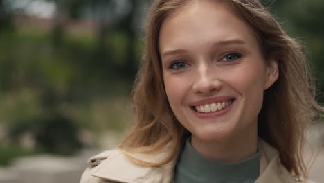 caucasian woman looking at the camera and smiling outdoors.