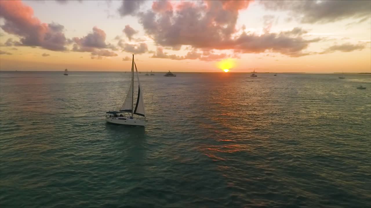 el velero flota mientras el sol se pone mientras un dron orbita alrededor del barco en una resolución nítida de 4k