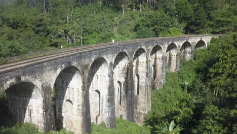 los turistas exploran la arquitectura del puente del tren de nueve arcos en sri lanka.