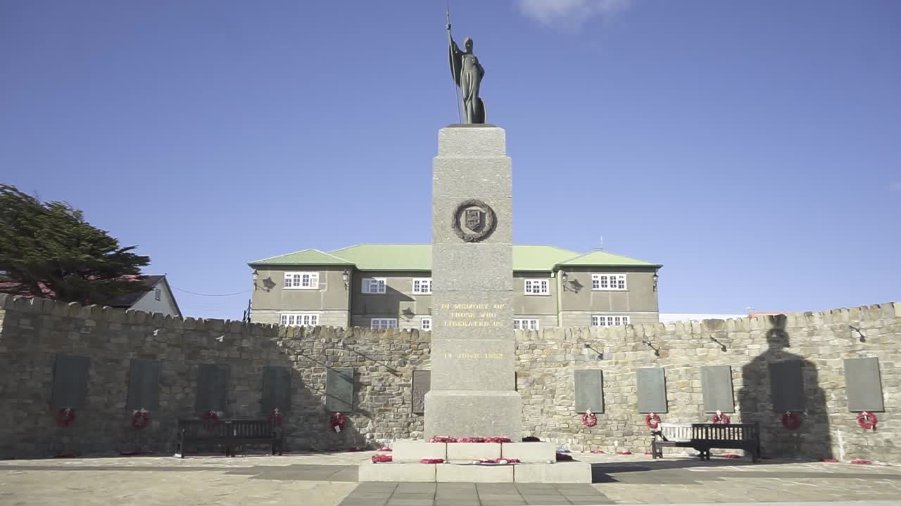 Camera pans across a stone war memorial with a statue of a soldier on top, commemorating the falkland islands war