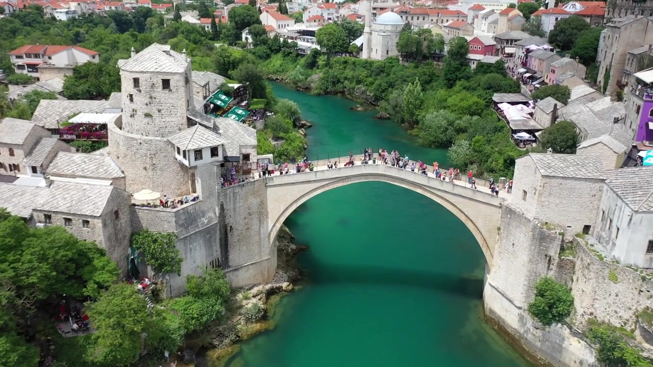 Vista aérea deslumbrante de drone da histórica Stari Most (Ponte Velha) sobre o rio Neretva cor de esmeralda em Mostar, Bósnia e Herzegovina. Apresenta arquitetura otomana tradicional e turistas