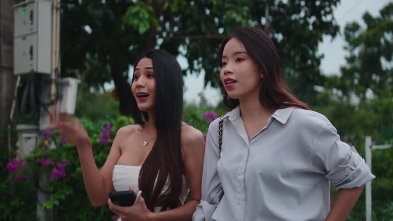 Two young women waving outdoors