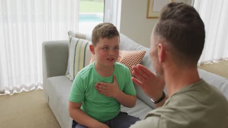 Caucasian-father-and-son-banging-their-chest-sitting-on-the-couch-at-home