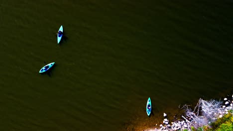 aerial fly over bird view 3 kayak rental users with individual inflatable boats on a polarized see through water from a beach launch to the mid area of the lake gather together to have some fun