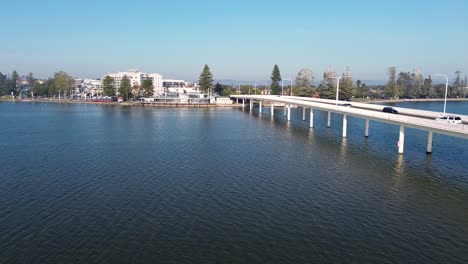 Drohnen-Luftschwenkaufnahme-Der-Eingangsbrücke,-Straße-über-Den-Kanaleingang,-Flussufer,-Gebäude,-Autos,-Wohnungen,-Einheiten,-Immobilien,-NSW,-Zentralküste,-Tourismus,-Reisen,-4k