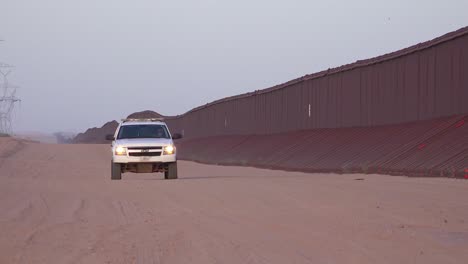 border patrol vehicle moves slowly near the border wall at the us mexico border at imperial sand dunes california 1