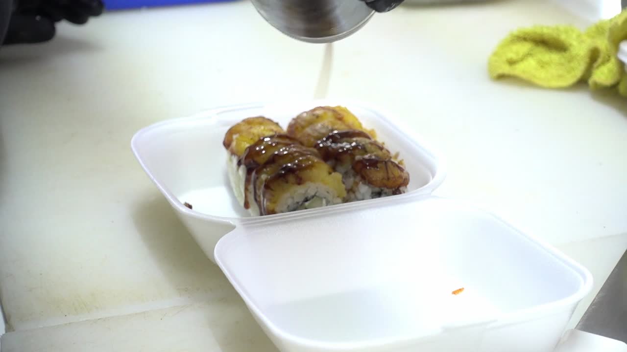 disparo en cámara lenta de rollos de sushi en caja cubiertos con salsa de soja para un cliente