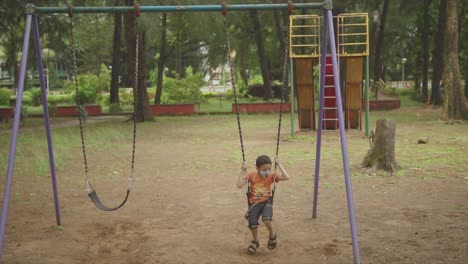 in a serene forest park, happy male child finds joy and relaxation as he sits on a wooden swing, embracing the warmth of the summer season