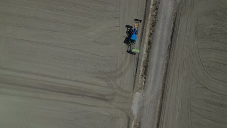a tractor working in gelsa zaragoza on dry, flat farmland during the day, aerial view