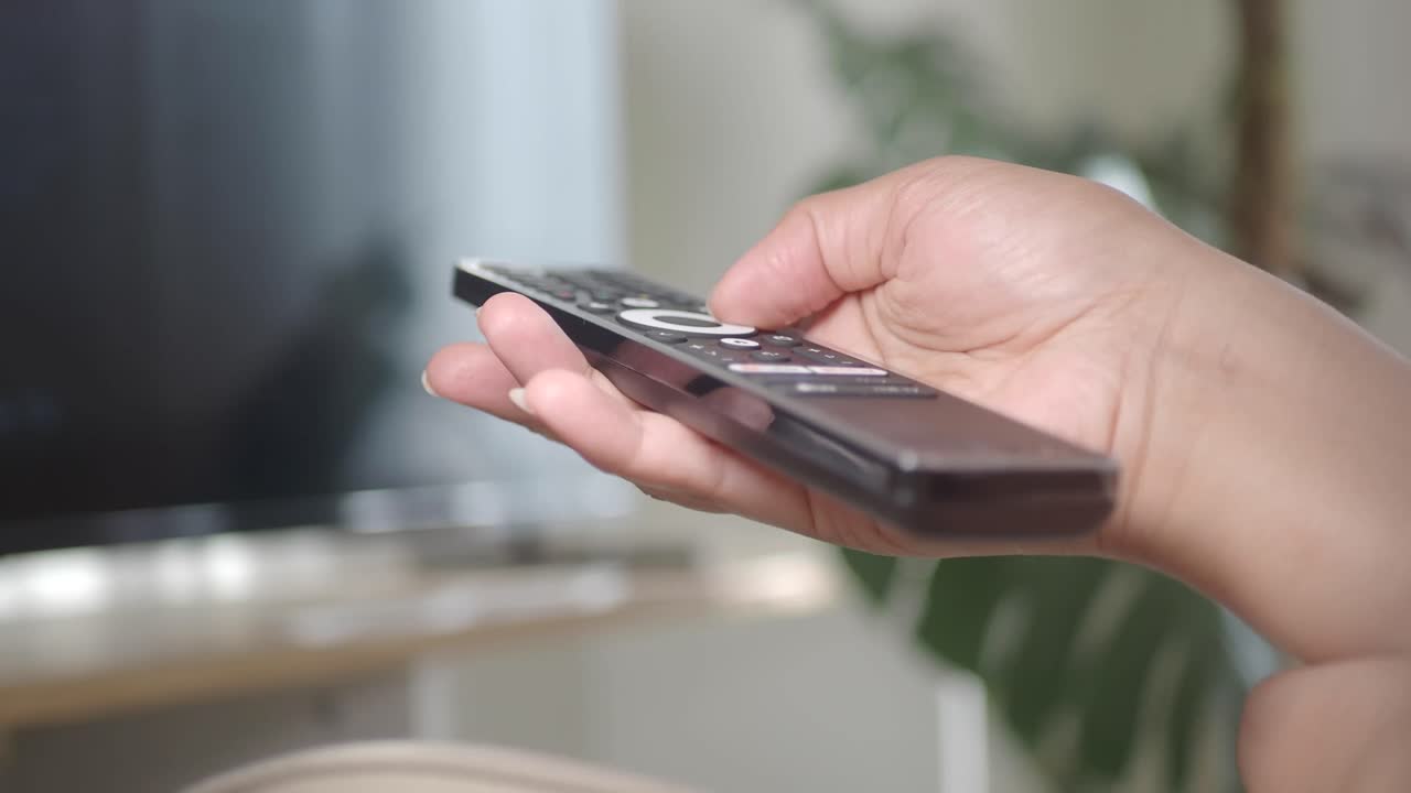 Close-up of hand holding a TV remote control