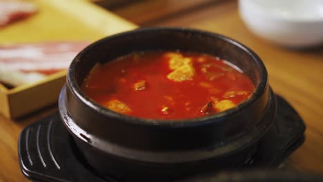 kimchi-eintopf – kimchi-jjigae, serviert in ttukbaegi in einem koreanischen restaurant