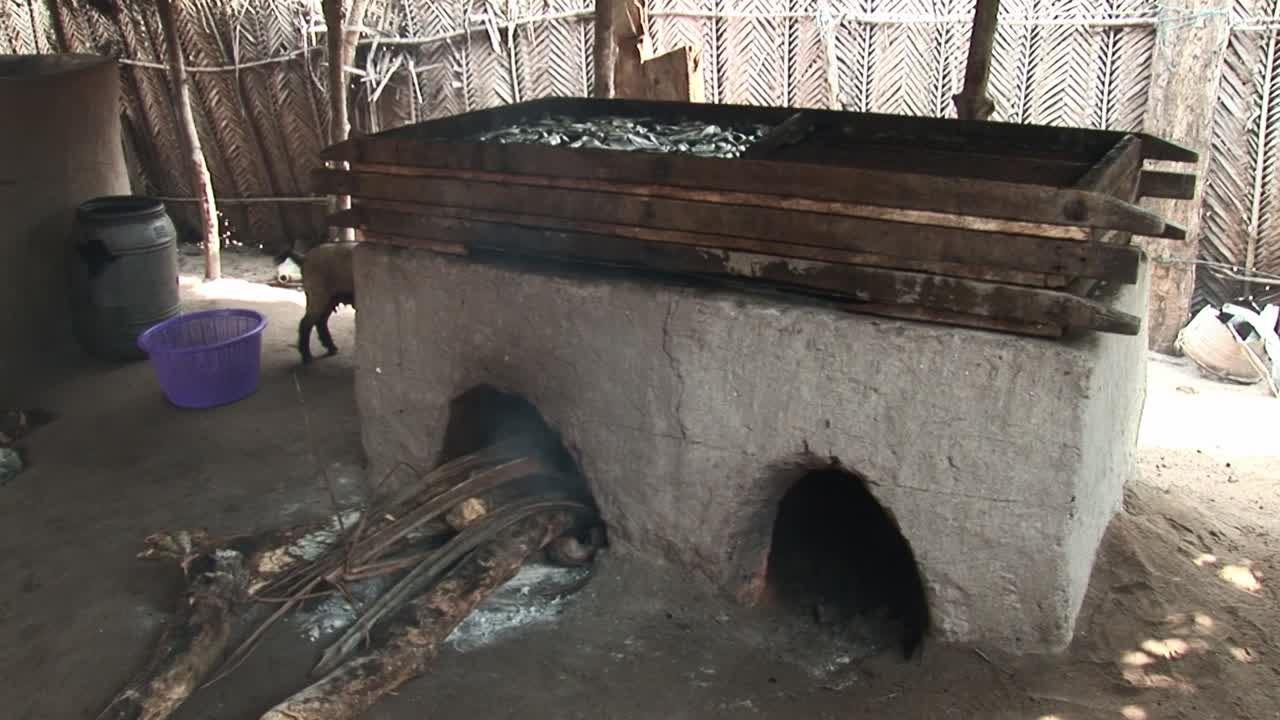 A traditional mud-built oven used for smoking fish, fueled by firewood. This method is used in West African fishing communities to preserve fish using sustainable, time-honored techniques