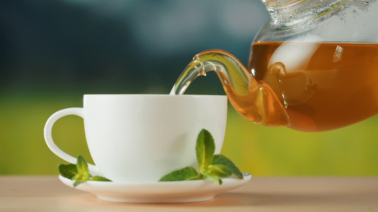 Pouring Tea into a White Cup with Mint