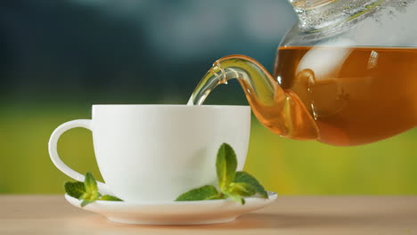 pouring tea into a white cup with mint