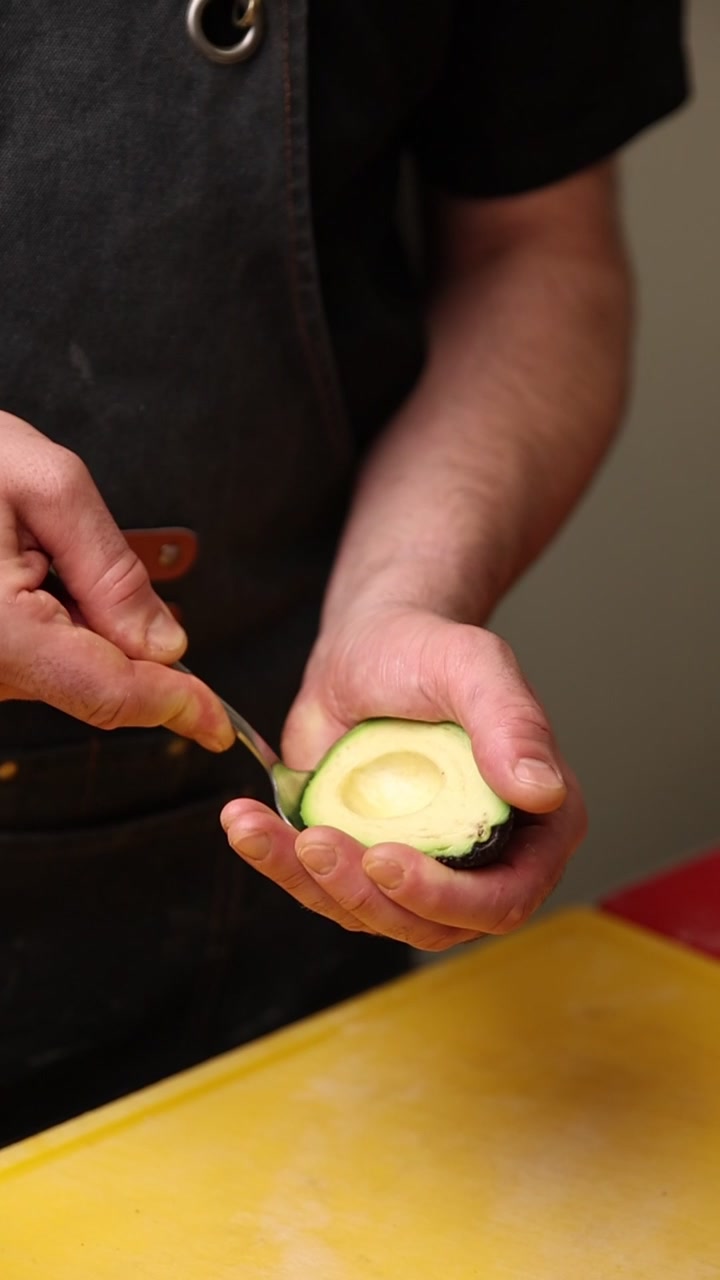 Primer plano de un chef sacando aguacate fresco de su piel