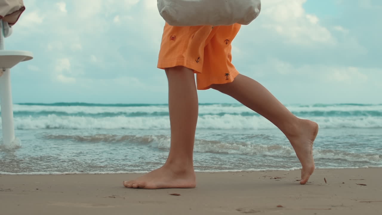 Giovane uomo sconosciuto che si gode le vacanze estive in spiaggia. Gambe di un ragazzo che cammina all'aperto.