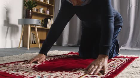 muslim woman wearing hijab at home kneeling on prayer mat and praying 2