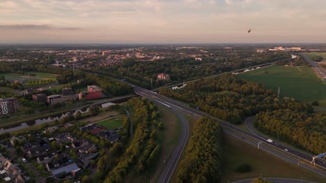 aerial view of a cityscape with highway and hot air balloon