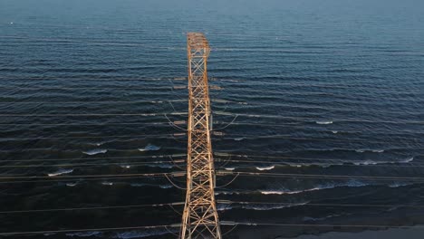 Torre-Eléctrica-Solitaria-De-Pie-En-Las-Tranquilas-Aguas-Del-Lago-Ontario-Cerca-De-Hamilton-Durante-El-Día