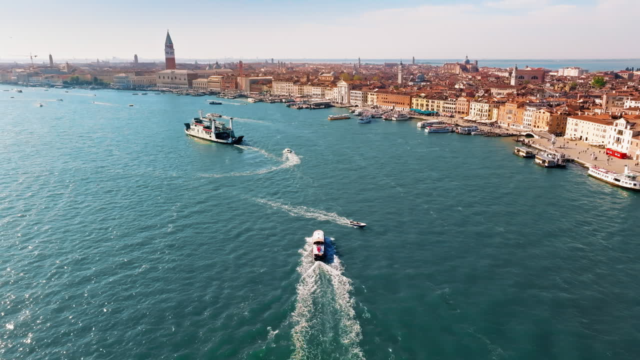 Aerial drone view of boats moving through Venice, Italy on a sunny day