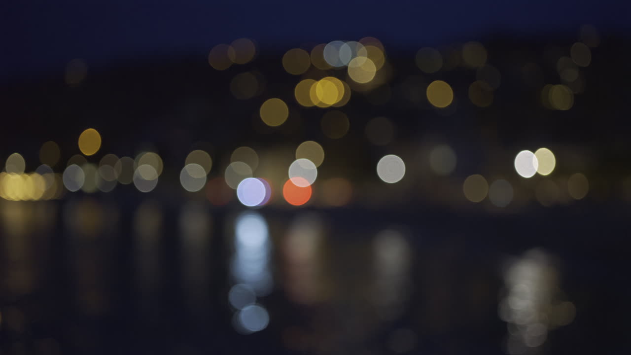 Blurred view of city lights reflecting on the sea in the evening