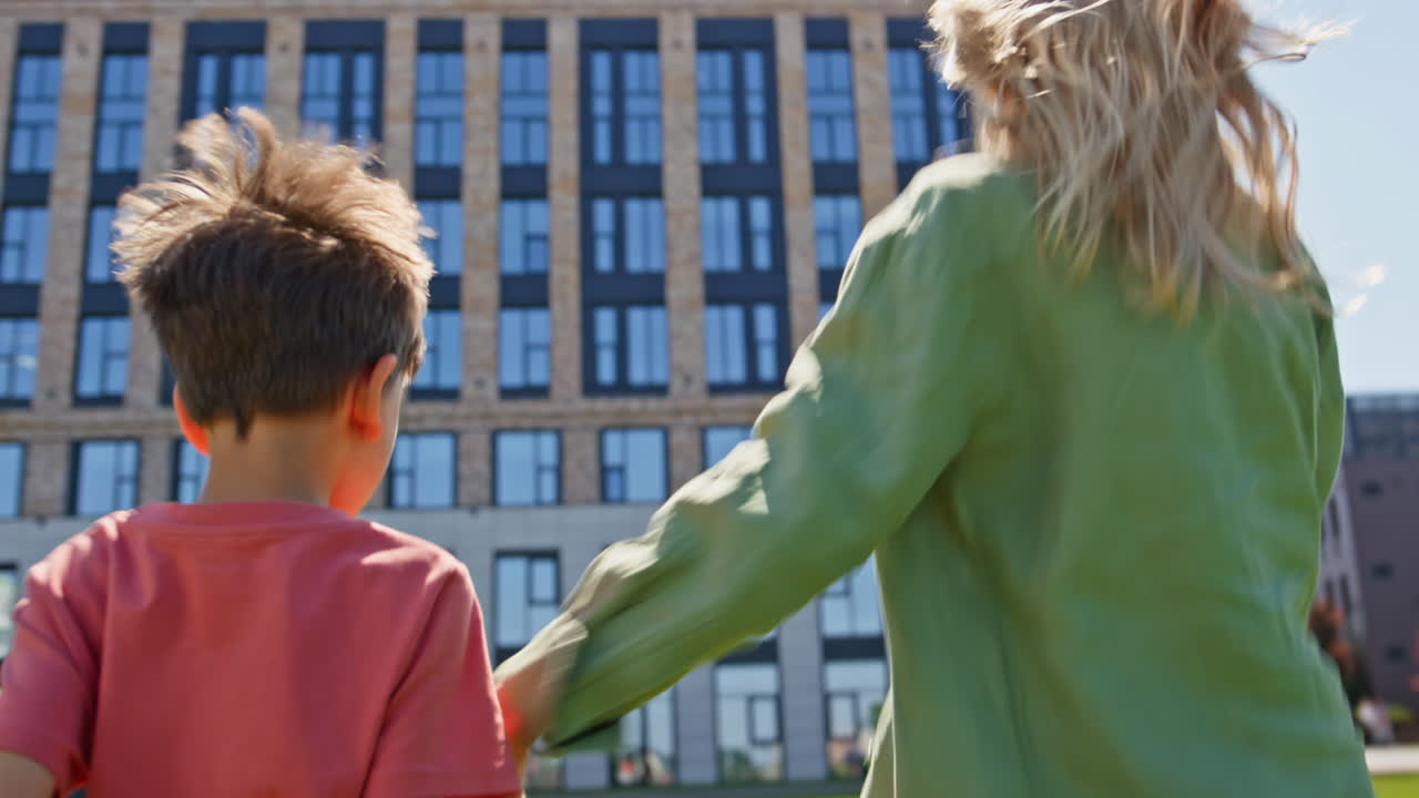 Joyful mother turning camera spreading arms at summer neighbourhood zone closeup