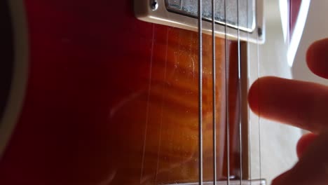 fingers picking the strings of a les paul electric guitar in cherry sunburst