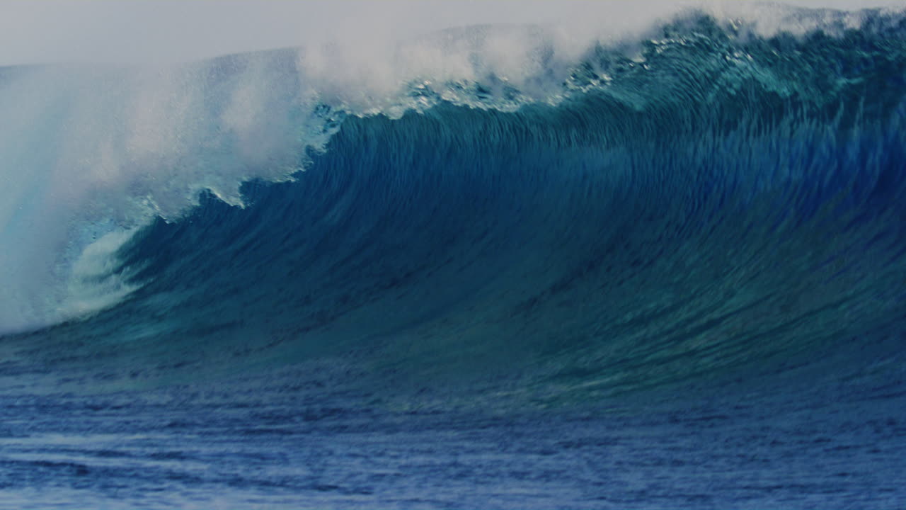 Strong blue wave rises up with strength as lip throws forward crashing into barrel