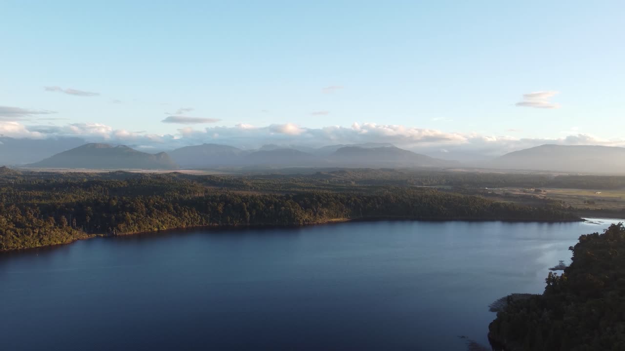 vista desde un avión no tripulado del lago mahinapua entre bosques y montañas durante la puesta de sol en hokitika, costa oeste, nueva zelanda