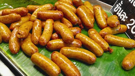 close-up panning shot of freshly cooked northern sausages served on a banana leaf at a street stand