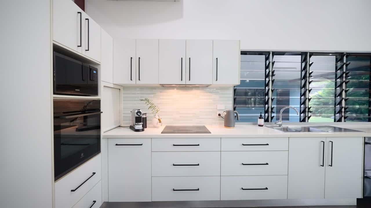 Cozinha de prestígio com detalhes em branco e preto, completa com fogão elétrico e eletrodomésticos de aço inoxidável ou pretos