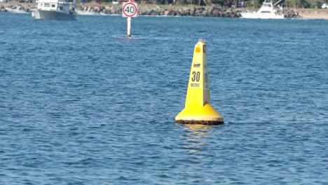 yellow buoy floating near boats and speed limit sign