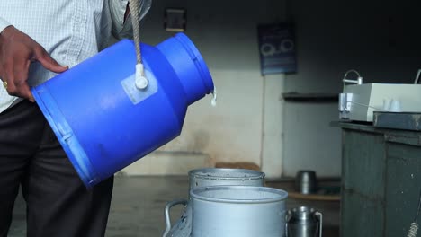 rural woman in southern india pouring milk at a milk pooling point, while the collection supervisor records the quantity of the milk & do the testing