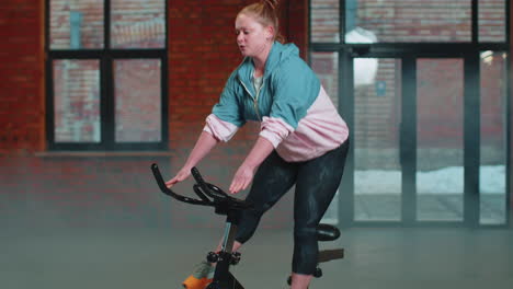 Mujer-Atlética-Montando-Una-Rutina-De-Entrenamiento-En-Bicicleta-Estacionaria-Giratoria-En-Un-Gimnasio-De-Niebla,-Pérdida-De-Peso-En-Interiores