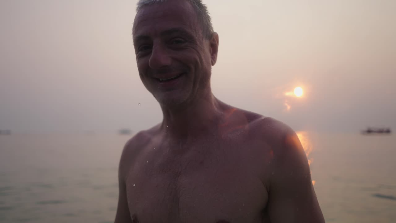 Happy man enjoying a swim in the sea at sunset