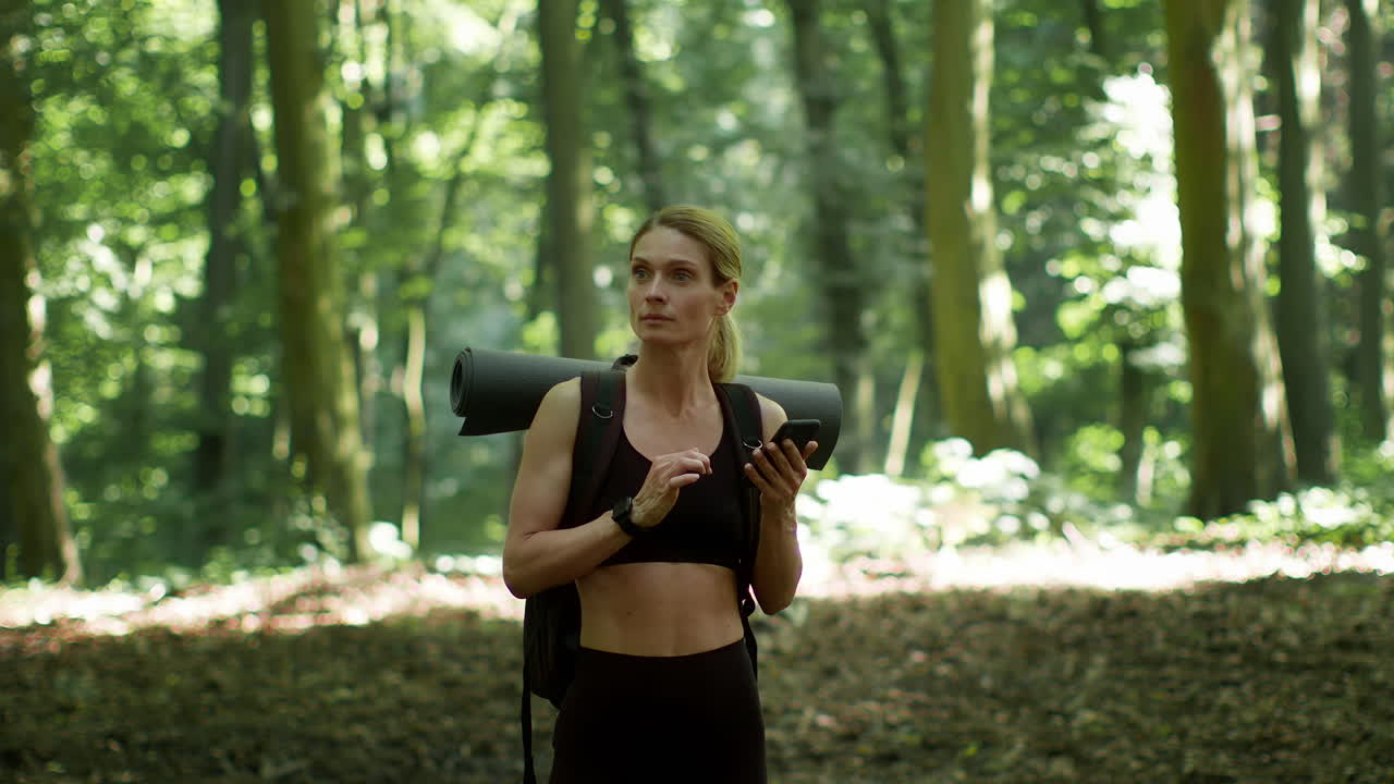 Woman using smartphone while hiking in a forest